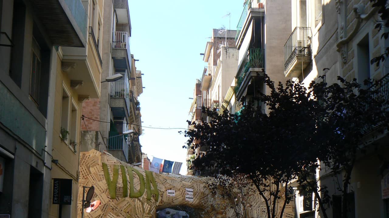 Calle estrecha de la Vila de Gràcia con balcones y decoración de la Fiesta Mayor
